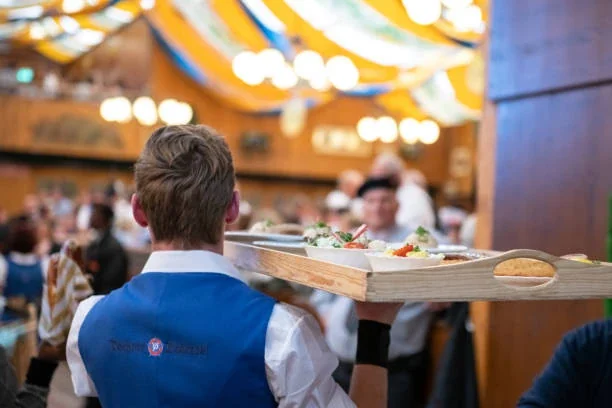 Festpersonal trägt ein Tablett durch ein Festzelt