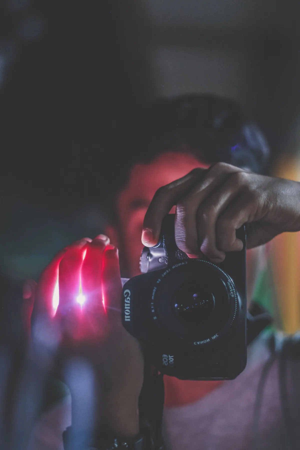 Eine Hand vor der Kamera – jemand fotografiert im roten Scheinwerferlicht